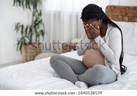 Sad Black Pregnant Woman Crying At Home, Having Maternity Depression, Suffering Hormonal Changes During Pregnancy, Desperate Lady Sitting On Bed In White Bedroom Covering Face With Hands, Copy Space Royalty-Free Stock Photo #1840538539