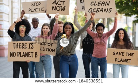Green peace activists international group of young people making strike on the street, walking with thematic placards and yelling through megaphone, fighting against environmental pollution Royalty-Free Stock Photo #1840538551