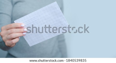 Woman holding Postal envelope in hand on gray background