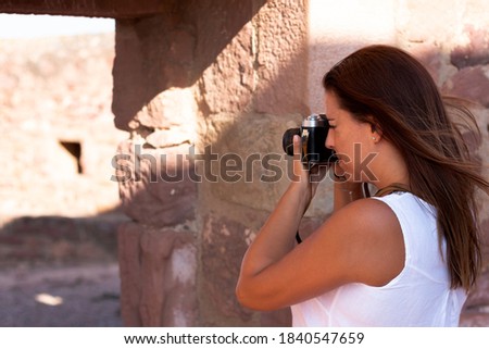 A young woman in white dress photographing with old camera on the street. Photography concept