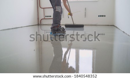 Master with a needle roller. Filling the floor. A contractor painter will paint the garage floor to speed up the sale of your home. Floor screed filling, repair and finishing. Fill in the low spots Royalty-Free Stock Photo #1840548352