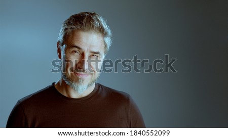 Portrait of happy older white man on gray background, smiling, copy space.