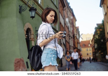 The girl in the black hat and sun glasses with photo camera on a road in an old european town. Euro summer trip.