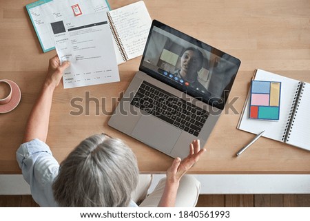 Mature senior employer hr checking indian female job applicant cv holding social distance remote online job interview by video conference call virtual chat meeting with recruit on laptop, top view. Royalty-Free Stock Photo #1840561993