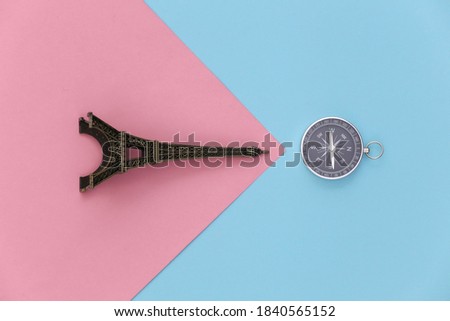Minimalism travel, adventure flat lay. Camera and eiffel tower figurine on a blue-pink pastel background. Top view