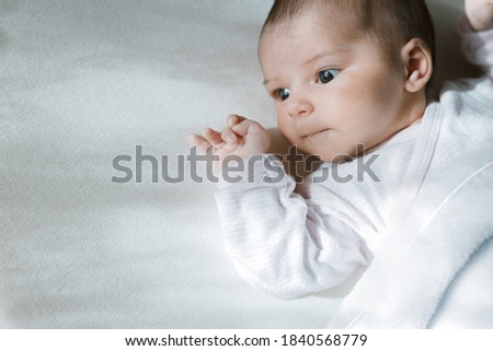 Adorable baby in a white sunny bedroom. Newborn baby is resting in bed. Family morning at home.