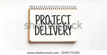 Notepad with text PROJECT DELIVERY. White background. Business