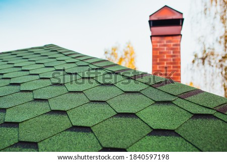 Roofing made of soft bitumen tiles of green color on the hipped roof of a country house Royalty-Free Stock Photo #1840597198