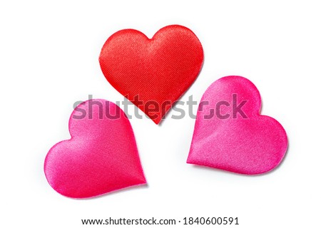 three textile hearts in red and pink fabric on a white background