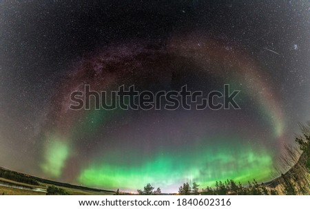 Rare amazing photo of whole Milky Way panorama matching Aurora Borealis red part (Steve phenomenon), green lights below, Northern Sweden landscape. 23 October 2020, Umea city, Vasterbotten county
