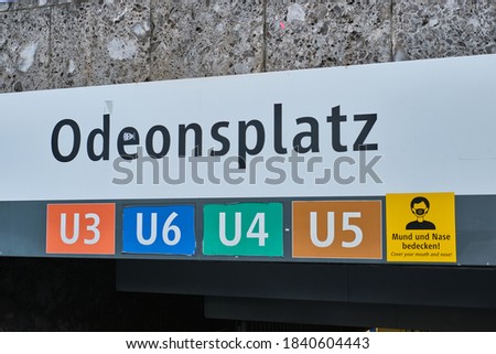 The sign of Odeonsplatz and the sign that warns people to cover their mouth and nose at a subway station in Munich, Germany. The sign of Odeonsplatz at a U-Bahn station. 