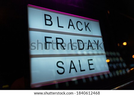 Lightbox Sign Black Friday Sale behind a glass door of the cafe at night. Concept Black friday, season sales time.