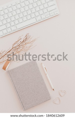 Stylish minimalistic workplace with keyboard, notebook on pastel pink background. flat lay, top view