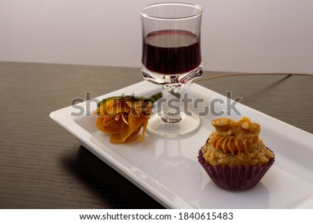 Plate with nut candy (camafeu de nozes), a glass of liquor and a flower