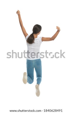 Back view of cheerful casual woman celebrating and jumping on white studio background