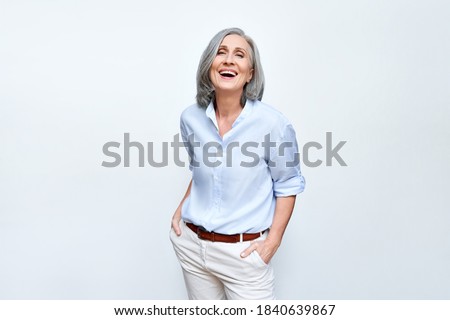 Happy elegant mature senior business woman laughing standing isolated on grey background. Smiling confident cheerful middle aged 60s lady with dental white smile looking at camera, copy space. Royalty-Free Stock Photo #1840639867