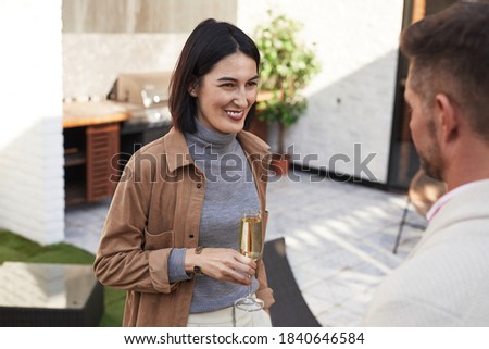 Waist up portrait of elegant modern woman smiling happily while talking to friend at outdoor party, copy space