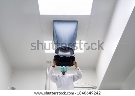 The unidentified operator is using the capture hood balometer to measuring the air velocity and volume of supply air from HVAC system in the clean room. Royalty-Free Stock Photo #1840649242