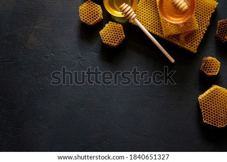 Jar of honey with honeycomb on black table, top view. space for text. Royalty-Free Stock Photo #1840651327