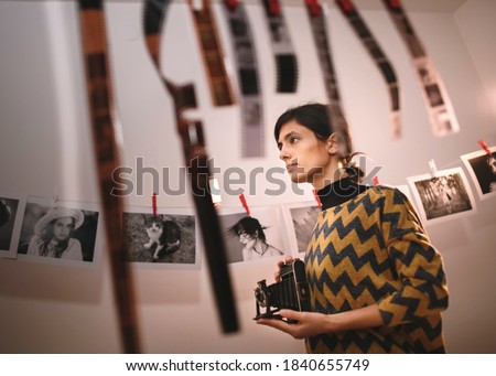 Female taking photo with old camera. Portrait of creative girl photographer in photo studio darkroom. Developing analog camera film