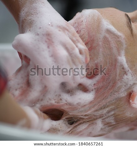  hairdresser's hands washing the client's pink hair with foam shampoo at the barber shop. High quality photo