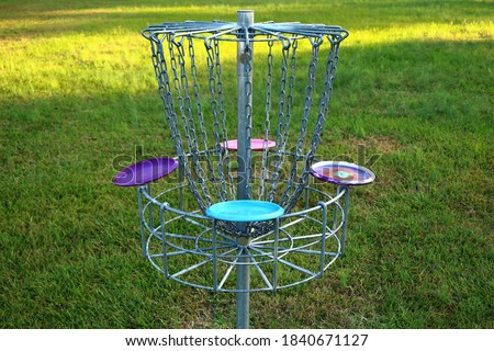 Picture of a disc golf basket with four colorful discs