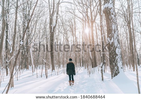 Winter forest walk woman hiking in snow with tall boots walking outdoors amongst trees. Royalty-Free Stock Photo #1840688464