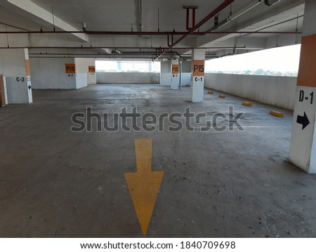 Empty car parking area in the tower building during covid-19 pandemi with yellow arrow direction on the floor