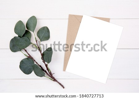 Blank paper sheet copy space with mockup and leaf on wooden table, card, poster and envelope, postcard decoration your design or branding, simplicity and minimal, nobody, flat lay, top view. Royalty-Free Stock Photo #1840727713