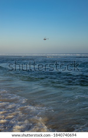 Peaceful seascape. Flying helicopter. Ocean with waves. Horizon line. Blue sky. Amazing view. Copy space. Vertical lay out. Melasti beach, Bali, Indonesia