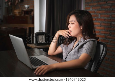 Asian businesswoman working late night tired sleepy overworked using computer laptop technology freelance business plan strategy work from home desk modern office during coronavirus COVID-19 pandemic