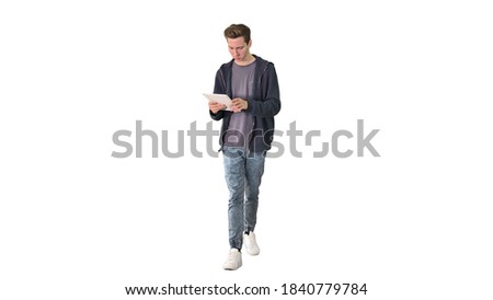 Casual man using tablet while walking on white background.