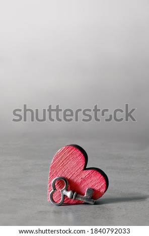 Silver key and red wooden heart on grey background. Valentines Day. Holiday concept.