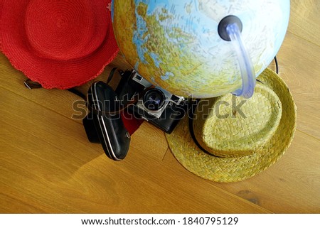 Straw hats, a globe and an old analog film photo camera ready for travel