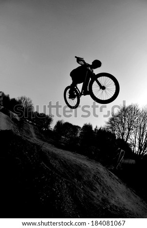 Silhouette of a young man performing a radical bmx jump 