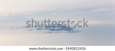 Panorama of the northern port town in the Arctic. Winter aerial view of the city of Anadyr, located on the coast of the Anadyr estuary, in the Far North of Russia. Chukotka, Siberia, Russian Far East.