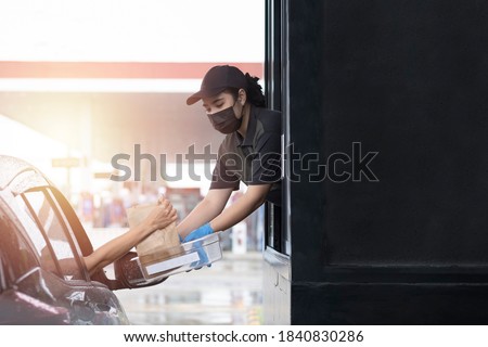 Drive through and takeaway for buy fast food for protect covid19. New normal life style. The staff woman wearing medical glove and mask and handed a food to customer. Drive thru and take away concept. Royalty-Free Stock Photo #1840830286