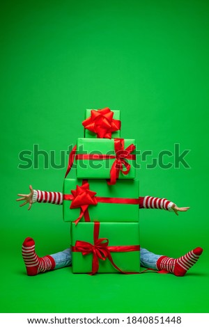 Because pyramid of green Christmas gift boxes on green background in Studio, you can see arms and legs stretched out in different directions. lot gifts for Christmas. Advertising and discounts.