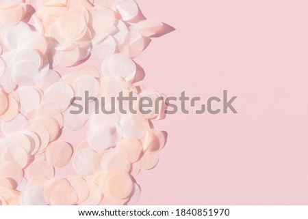 white pink and paper confetti on a pastel pink background border with copy space