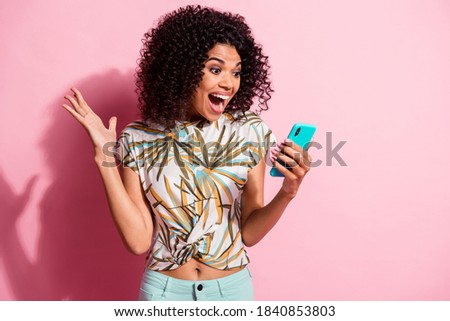 Photo portrait of shocked screaming girl unexpectedly winning holding phone in hand isolated on pastel pink colored background