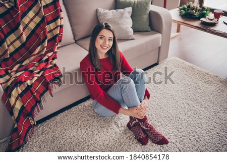 Photo of pretty lady sit floor sofa look camera hug legs wear red sweater socks jeans in decorated x-mas living room indoors