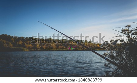 Fishing rod with a bell on the lake in the autumn. Toned photo with the vignetting.
