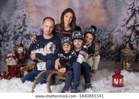 Happy family, parents with three children and puppy dog, having christmas pictures taken in the snow
