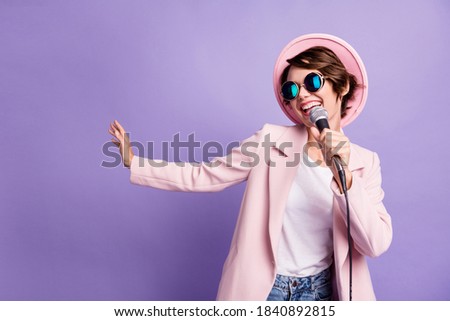 Photo of adorable pretty bob hair young lady wear cap coat glasses singing in mike isolated on violet color background