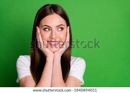 Photo portrait of woman touching face cheeks with two hands looking at blank space isolated on vivid green colored background