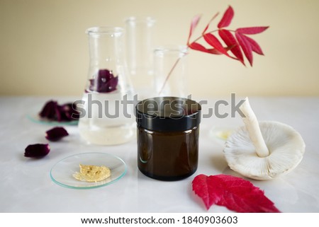 
cosmetic jar with cream on the background of laboratory flasks with different natural ingredients. The concept of natural ingredients in cosmetics