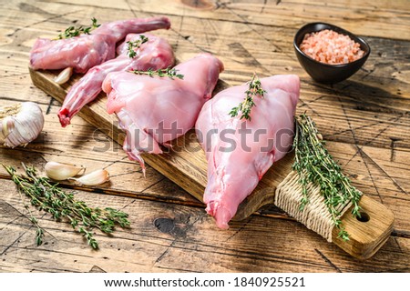 Raw rabbit legs on a cutting Board. Wooden background. Top view