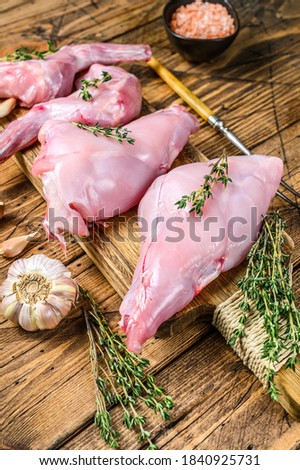 Raw rabbit legs on a cutting Board. Wooden background. Top view
