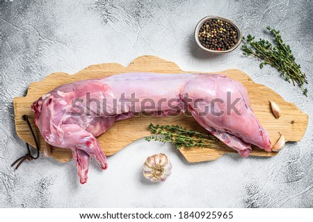 Whole raw rabbit on a cutting board. Gray background. Top view