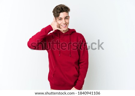 Young caucasian man isolated on white background showing a mobile phone call gesture with fingers.